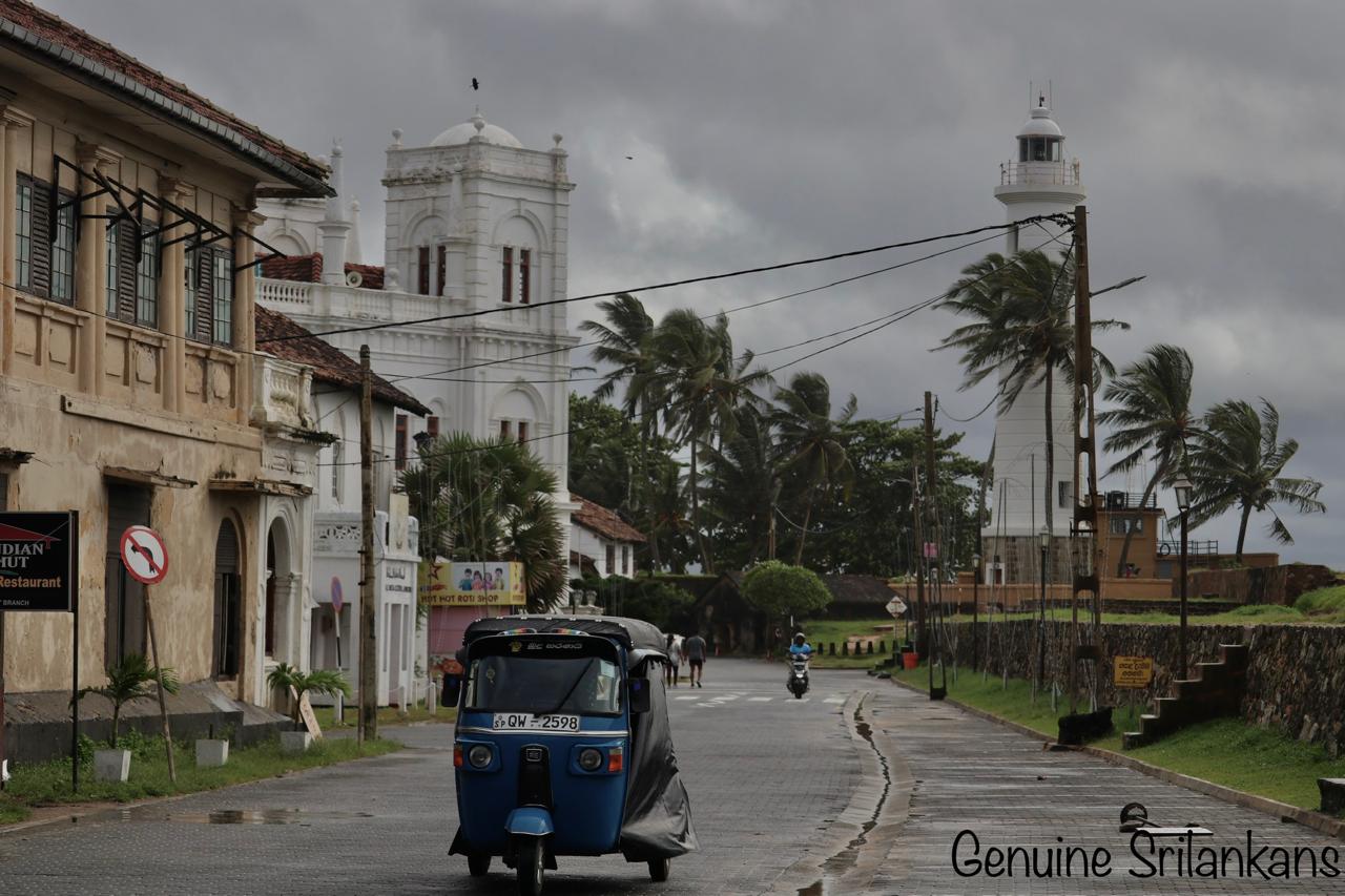 Galle Fort lighthouse with a blue tuk-tuk on the colonial street